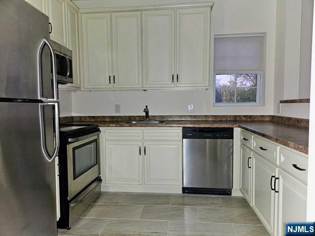 6 Madison Avenue, Unit 303 Cresskill, NJ 07626 - Photo 3 of 12 a kitchen with granite countertop white cabinets and stainless steel appliances