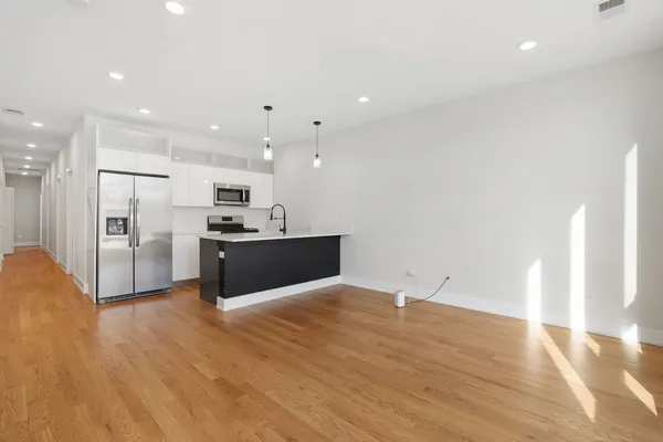 a view of kitchen with kitchen island white cabinets and stainless steel appliances