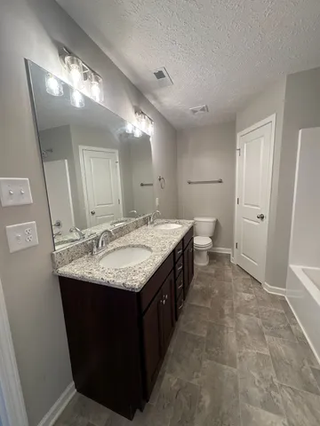 a bathroom with a granite countertop sink a toilet and a mirror