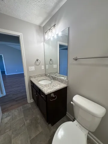a bathroom with a granite countertop toilet a sink and a mirror