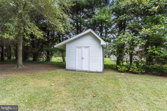 a view of a house with a yard and large trees