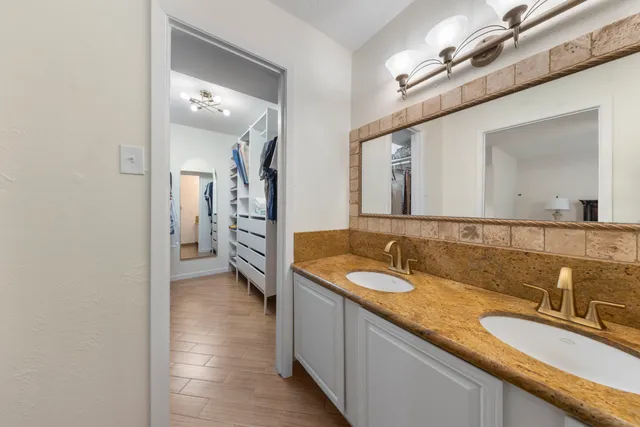 a en suite bathroom with a granite countertop sink and a mirror