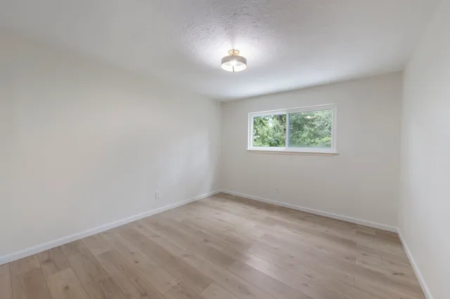 an empty room with windows and hardwood floor