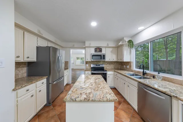 a kitchen with stainless steel appliances granite countertop a sink stove and refrigerator