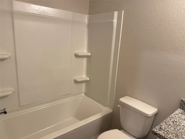a white toilet sitting next to a bath tub