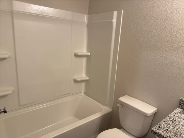 a white toilet sitting next to a bath tub
