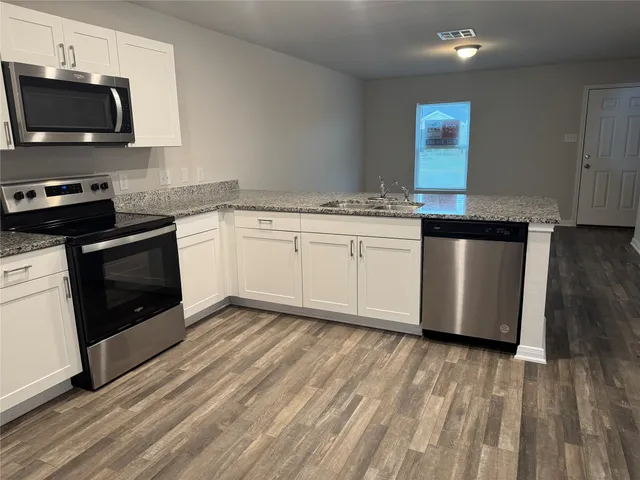 a kitchen with stainless steel appliances granite countertop a stove a sink and a microwave