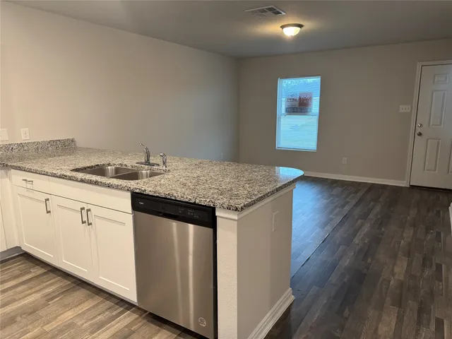 a kitchen with a sink cabinets and wooden floor
