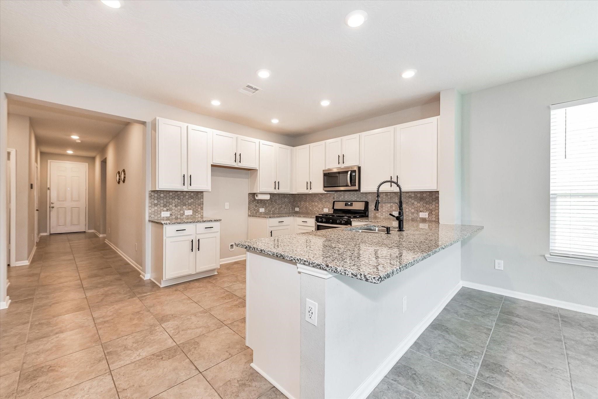 1111 Swinford Court Conroe, TX 77304 - Photo 6 of 21 a kitchen with stainless steel appliances granite countertop a stove top oven a sink a refrigerator and white cabinets