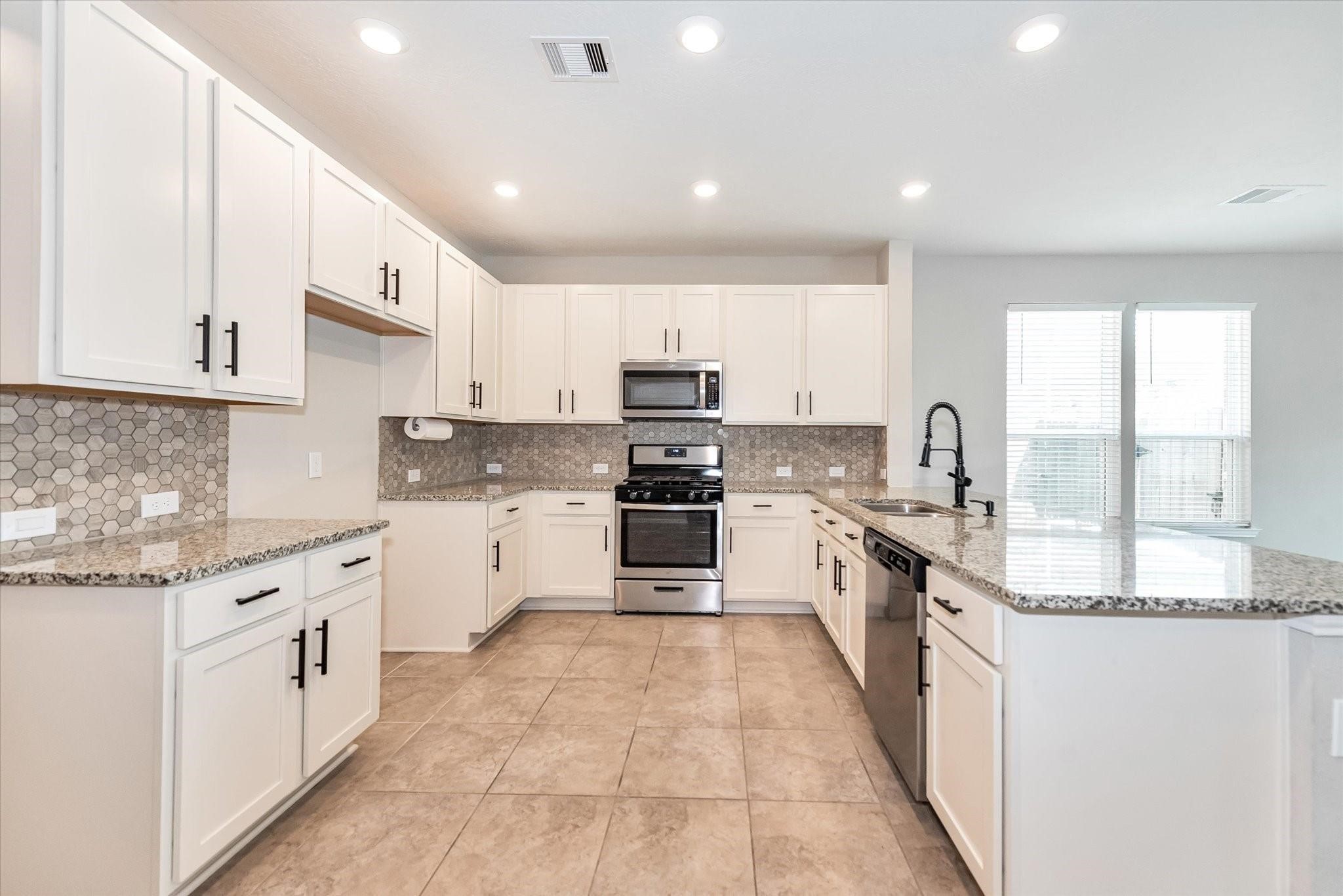 1111 Swinford Court Conroe, TX 77304 - Photo 8 of 21 a large kitchen with stainless steel appliances granite countertop a stove and a sink