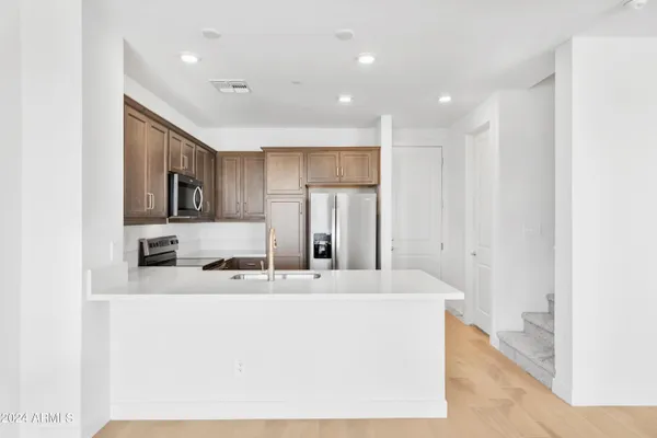 a room with kitchen island a sink stainless steel appliances and cabinets
