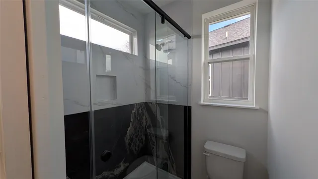 a bathroom with a granite countertop sink a toilet and a window