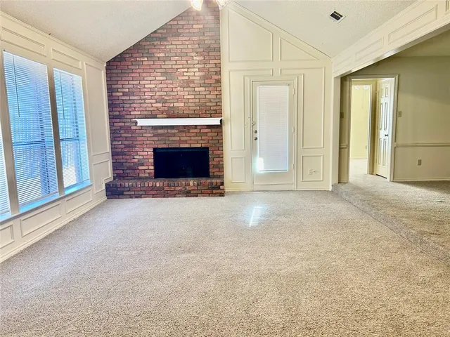 an empty room with windows and fireplace