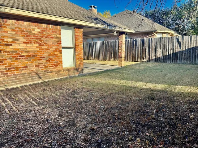 a view of a backyard with plants and wooden fence