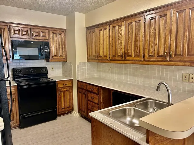 a kitchen with granite countertop a stove a sink and a microwave