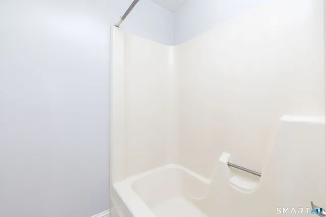 a bathroom with a white bath tub and a white shower