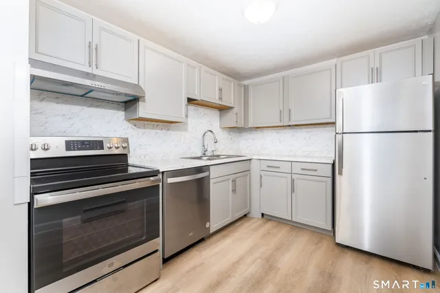 a kitchen with cabinets appliances and a wooden floor