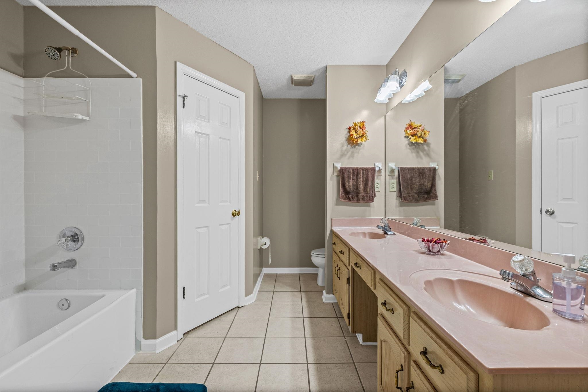 7788 Reese Road Memphis, TN 38133 - Photo 17 of 23 Bathroom featuring a double vanity with integrated sinks, a wide mirror, and a new bathtub with shower, double closets