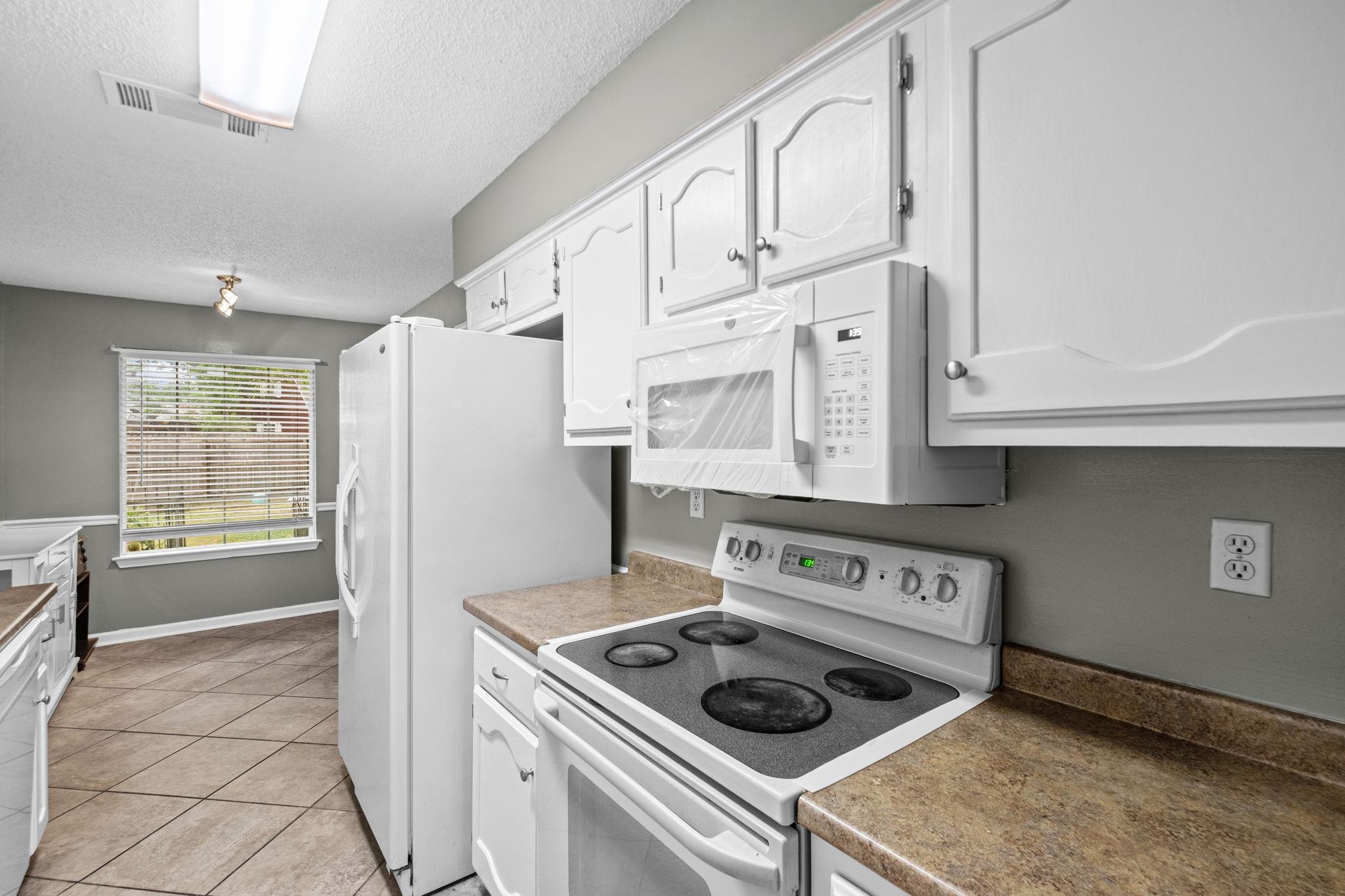 7788 Reese Road Memphis, TN 38133 - Photo 6 of 23 Kitchen featuring white cabinetry with decorative molding, a built-in microwave, an electric range, and laminate countertops