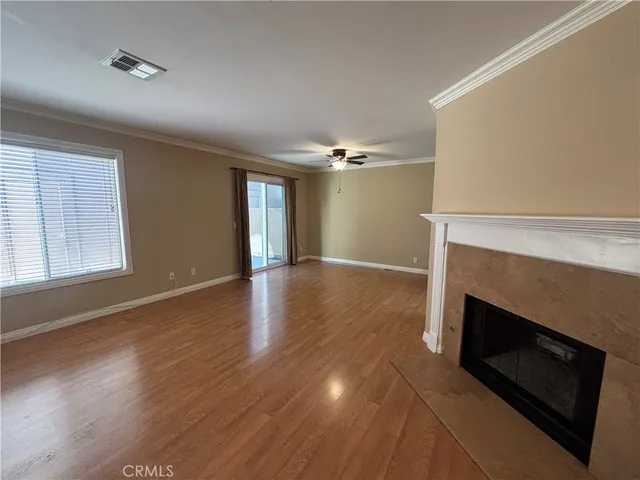a view of an empty room with wooden floor and a fireplace