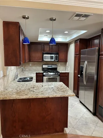 a kitchen with stainless steel appliances granite countertop a refrigerator a stove a sink and a microwave