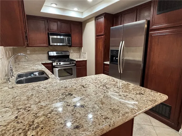 a kitchen with stainless steel appliances granite countertop a refrigerator stove top oven a sink and dishwasher
