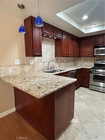 a kitchen with kitchen island granite countertop a sink cabinets and stainless steel appliances
