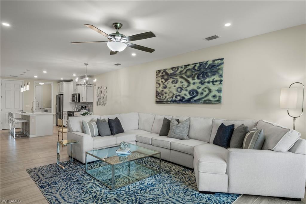 14680 Edgewater Circle Naples, FL 34114 - Photo 11 of 33 a living room with furniture a rug and a chandelier