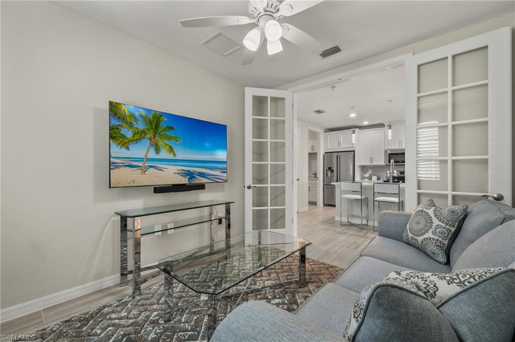 14680 Edgewater Circle Naples, FL 34114 - Photo 16 of 33 a living room with furniture a flat screen tv and kitchen view