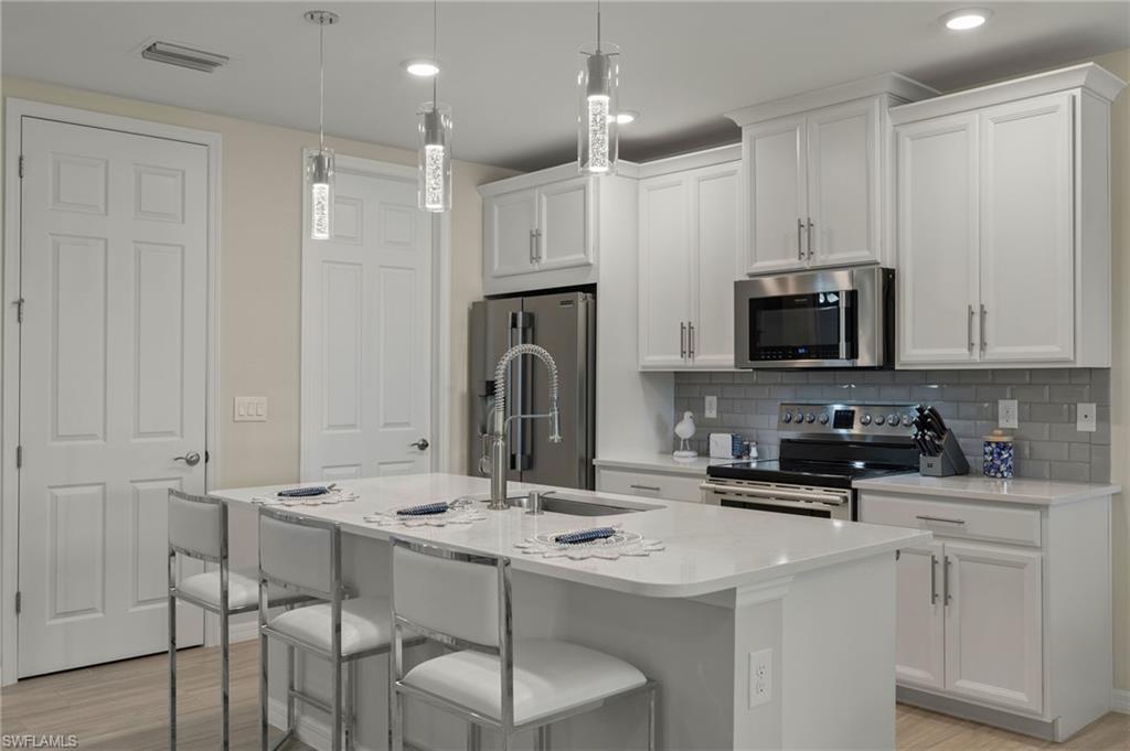 14680 Edgewater Circle Naples, FL 34114 - Photo 4 of 33 a kitchen with stainless steel appliances kitchen island a sink a microwave and cabinets