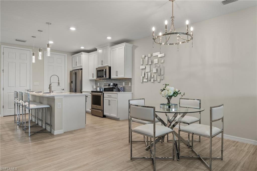 14680 Edgewater Circle Naples, FL 34114 - Photo 7 of 33 a kitchen with kitchen island stainless steel appliances a dining table chairs sink and cabinets