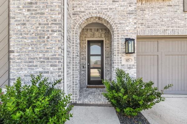 1825 Rough Rdg Trail Midlothian, TX 76065 - Photo 5 of 37 Arched entryway with a dark-frame glass-panel door, complemented by light grey brickwork