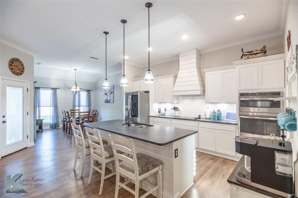 138 Lisa Lane Tuscola, TX 79562 - Photo 9 of 38 a kitchen with stainless steel appliances granite countertop a stove top oven a sink a dining table and chairs with wooden floor