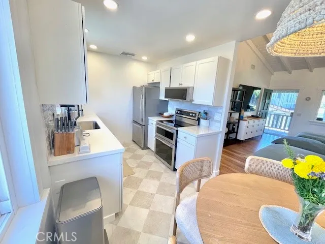 a kitchen with stainless steel appliances kitchen island granite countertop a sink a stove a dining table and chairs with wooden floor