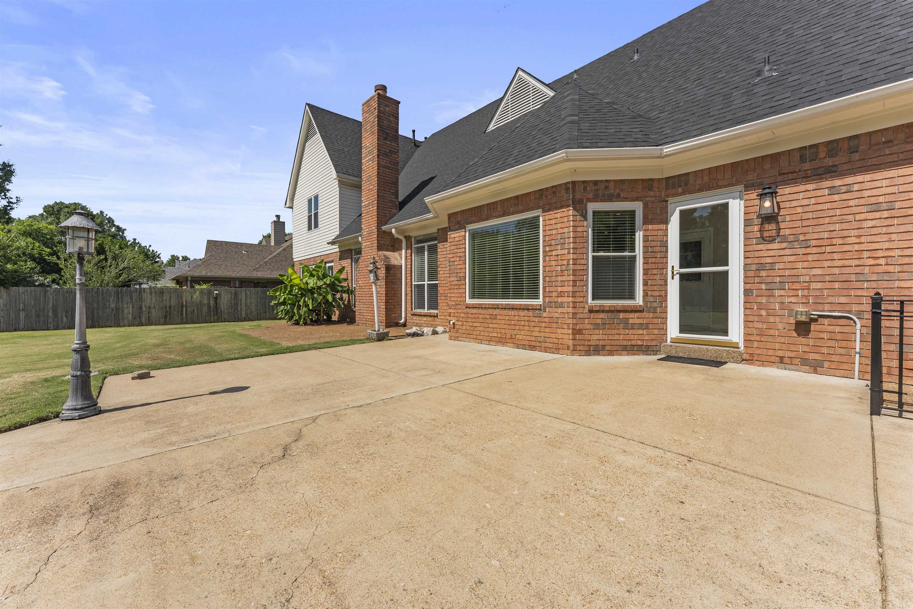 4279 High Plains Road Bartlett, TN 38135 - Photo 28 of 37 Expansive concrete patio area with a brick exterior, multiple windows, and a glass-paneled exterior door