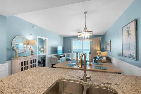 a view of a kitchen with kitchen island a sink wooden floor and a chandelier