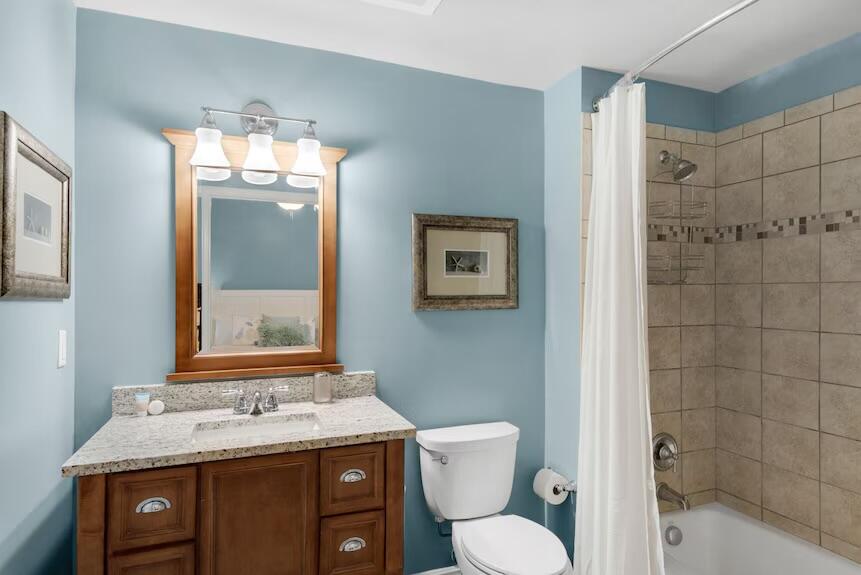 16701 Front Beach Road, Unit 401 Panama City Beach, FL 32413 - Photo 18 of 22 a bathroom with a granite countertop toilet a sink and a mirror
