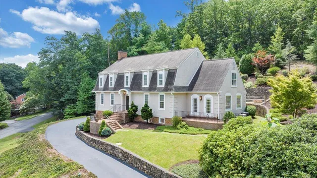 a front view of a house with garden and trees