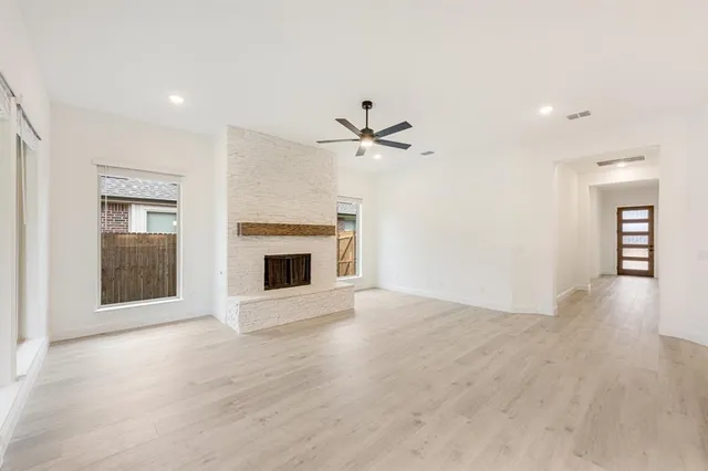 a view of a livingroom with a fireplace a ceiling fan and wooden floor