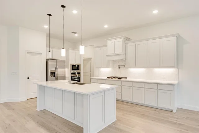 a kitchen with stainless steel appliances granite countertop a sink a stove and a refrigerator