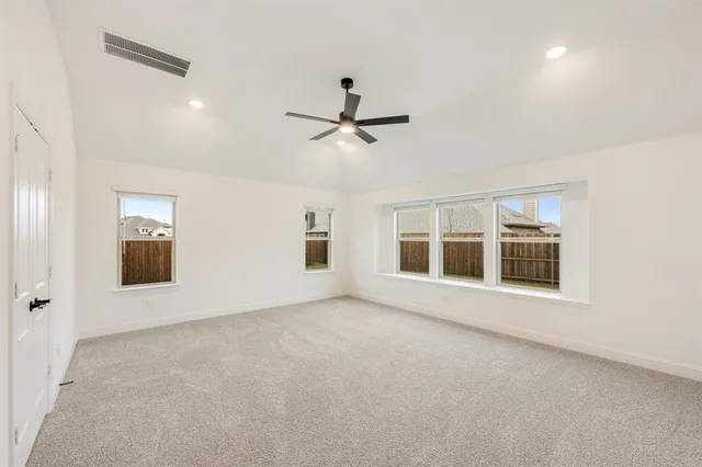 an empty room with ceiling fan and windows