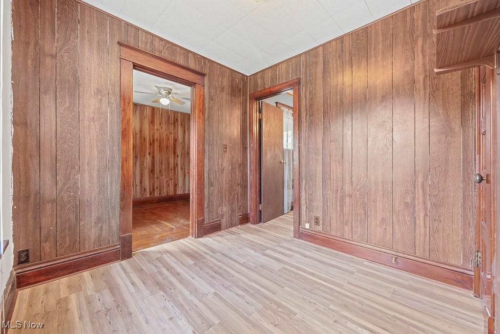 2725 Linwood Road Akron, OH 44312 - Photo 21 of 38 Empty room with ceiling fan, light wood-type flooring, and wood walls