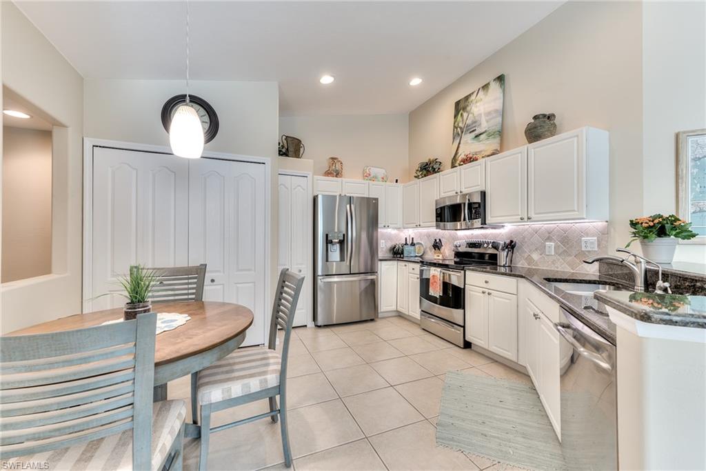 9281 Spring Run Boulevard, Unit 2602 Estero, FL 34135 - Photo 12 of 36 a kitchen with stainless steel appliances granite countertop a stove a sink dishwasher and a refrigerator with white cabinets