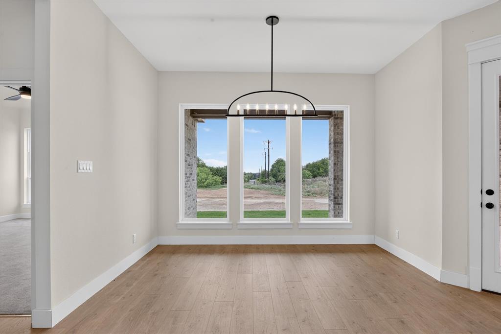 471 Red Bird Drive Springtown, TX 76082 - Photo 14 of 35 Spacious room featuring wood-finish flooring, light-colored walls, and a modern black chandelier