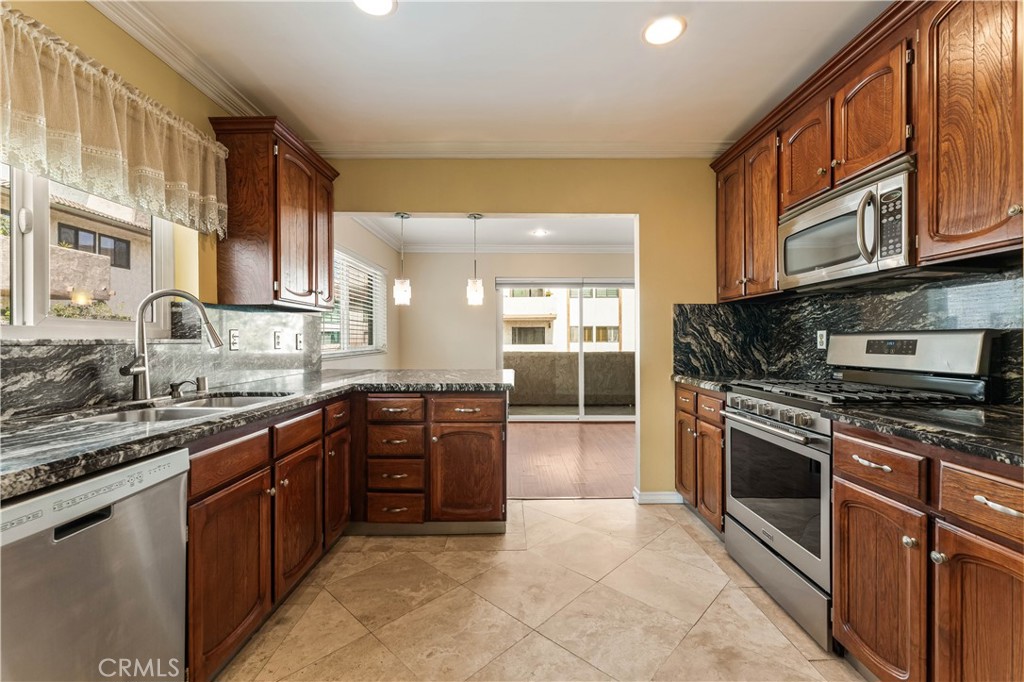 12300 Montecito Road, Unit 42 Seal Beach, CA 90740 - Photo 8 of 44 a large kitchen with stainless steel appliances granite countertop a stove top oven a sink dishwasher a dining table and chairs with wooden cabinets