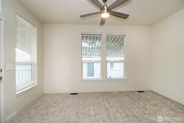 an empty room with chandelier fan and windows