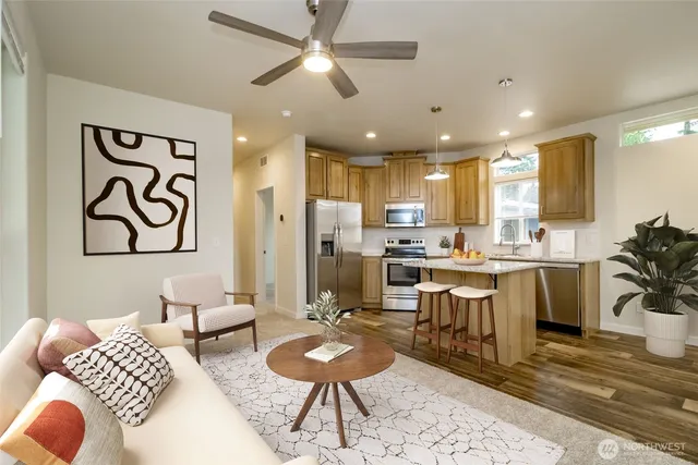 a kitchen with stainless steel appliances kitchen island granite countertop a refrigerator a sink a stove and white cabinets with wooden floor