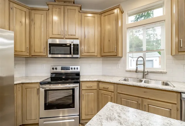 a kitchen with appliances a sink and a window