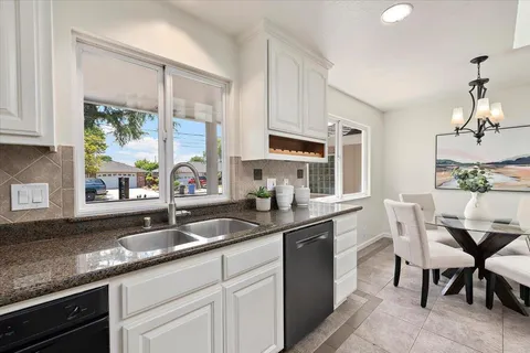 a kitchen with granite countertop a sink and white cabinets