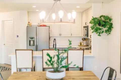a kitchen with stainless steel appliances a refrigerator a stove a microwave oven a sink a dining table and chairs